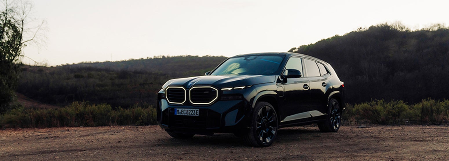 Black BMW XM parked with a forest background | BMW Showcase 1 in Derwood MD