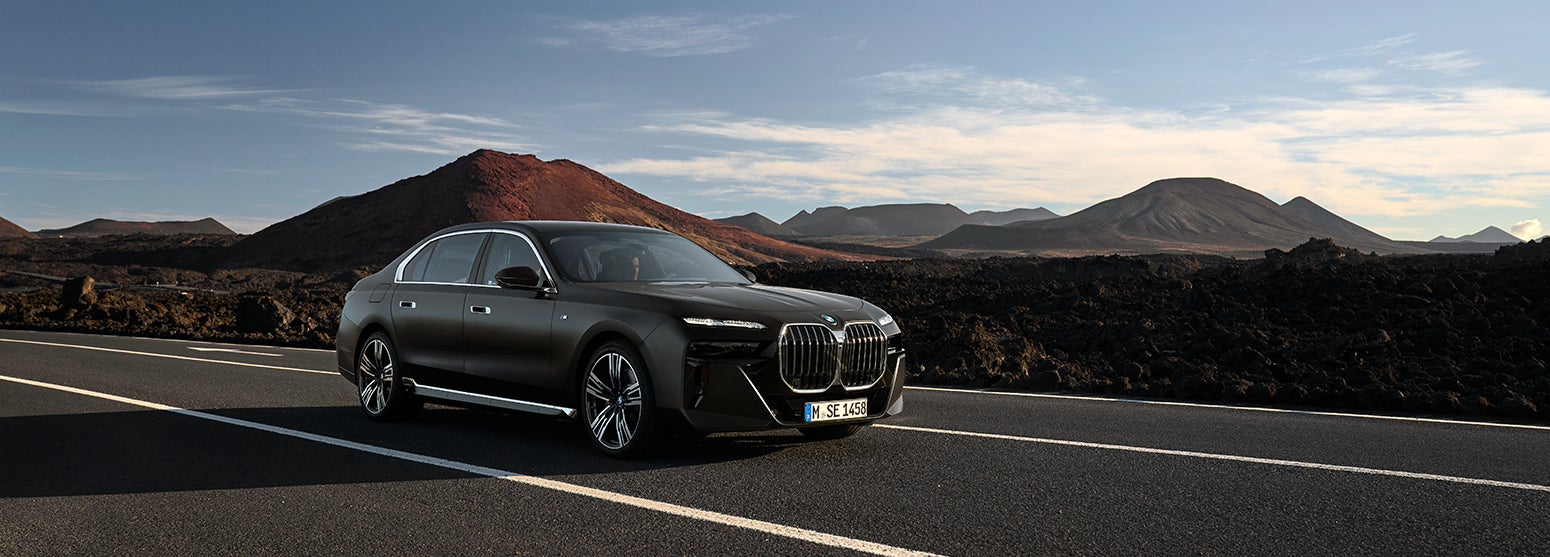 Black BMW i7 driving down road with mountainous background | BMW Showcase 1 in Derwood MD